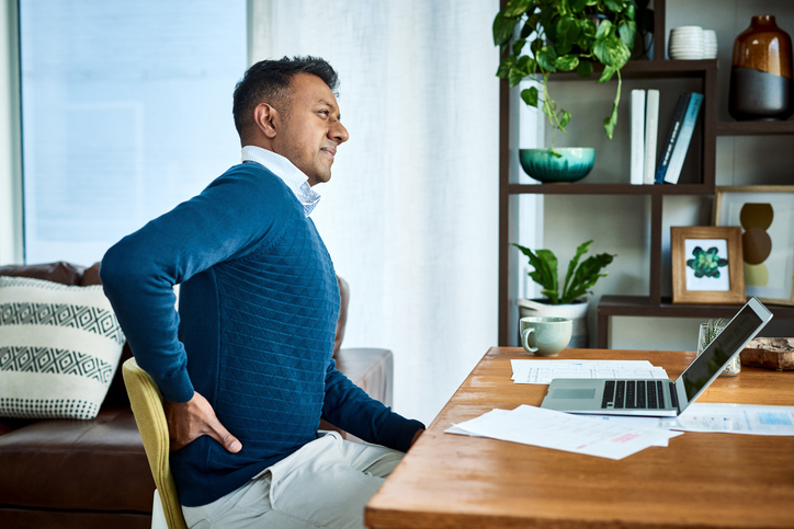 Shot of a businessman suffering from back pain while working at home